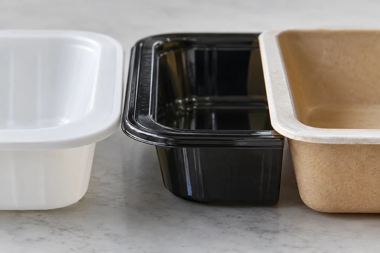 Gros plan de trois rebords de barquettes sans marque : un rebord lisse, un rebord noir brillant et un rebord en carton.